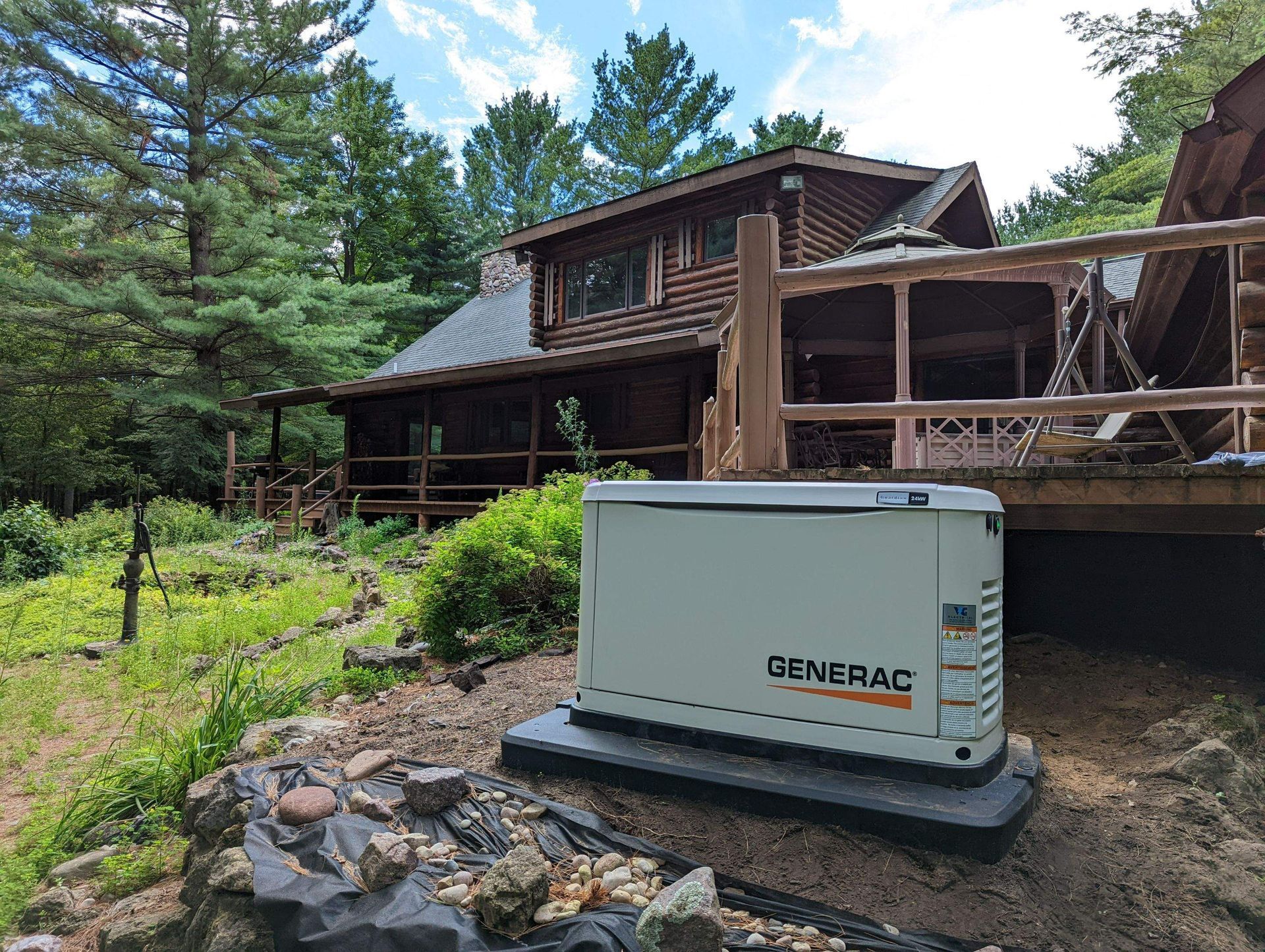 A generator is sitting in front of a log cabin.