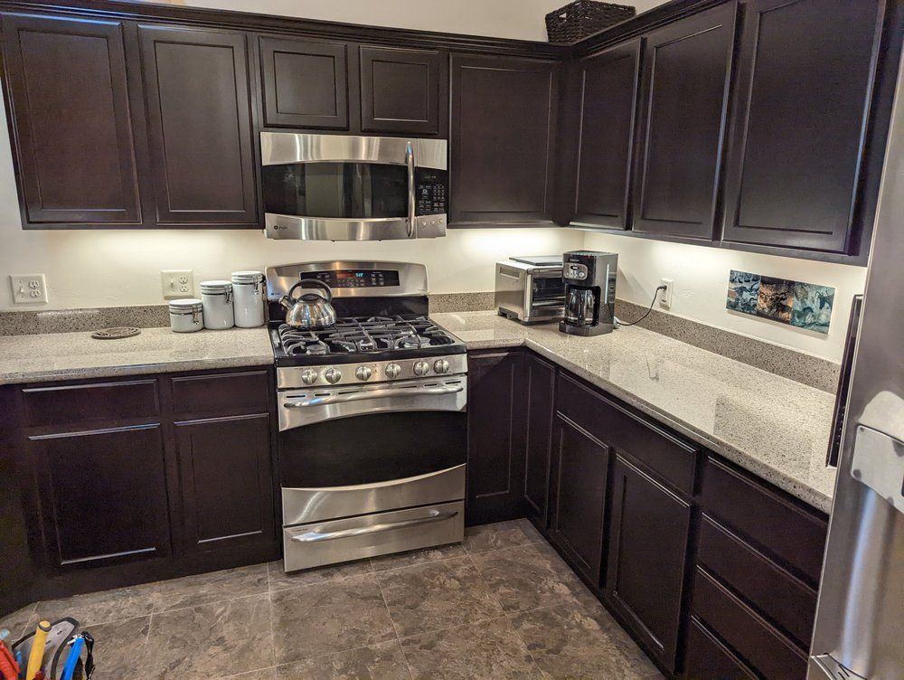 A kitchen with dark cabinets , stainless steel appliances , and granite counter tops.