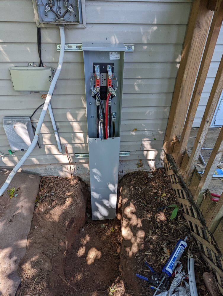 A electrical box is being installed on the side of a house.