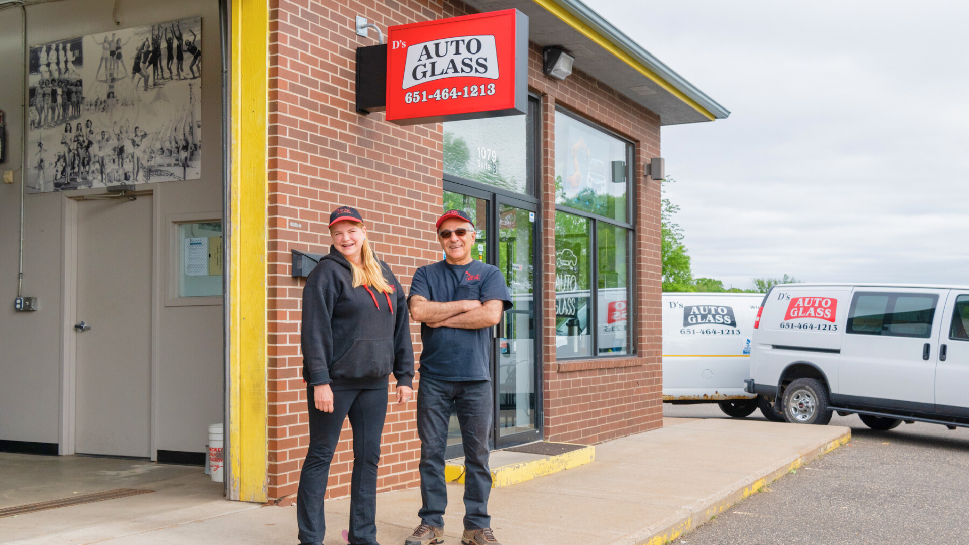 A man and a woman are standing in front of a brick building.