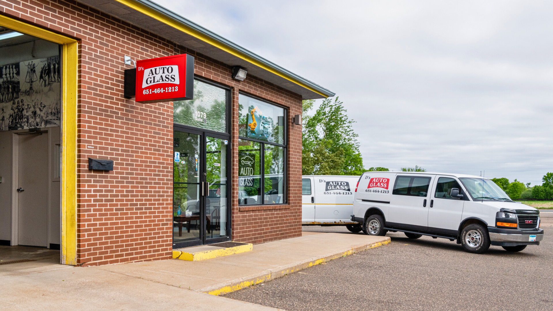 A white van is parked in front of a brick building.