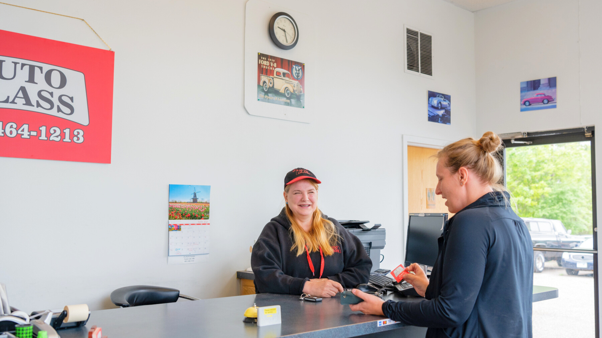 A woman is sitting at a counter in a store talking to another woman.