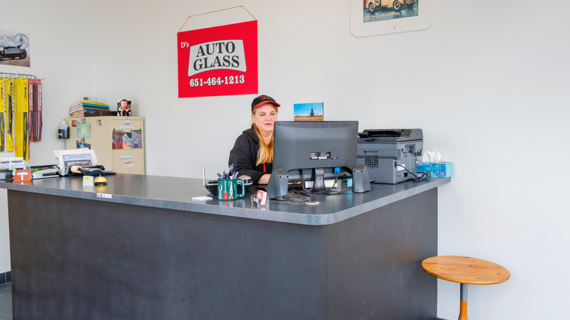 A man is sitting at a counter in an auto glass shop.