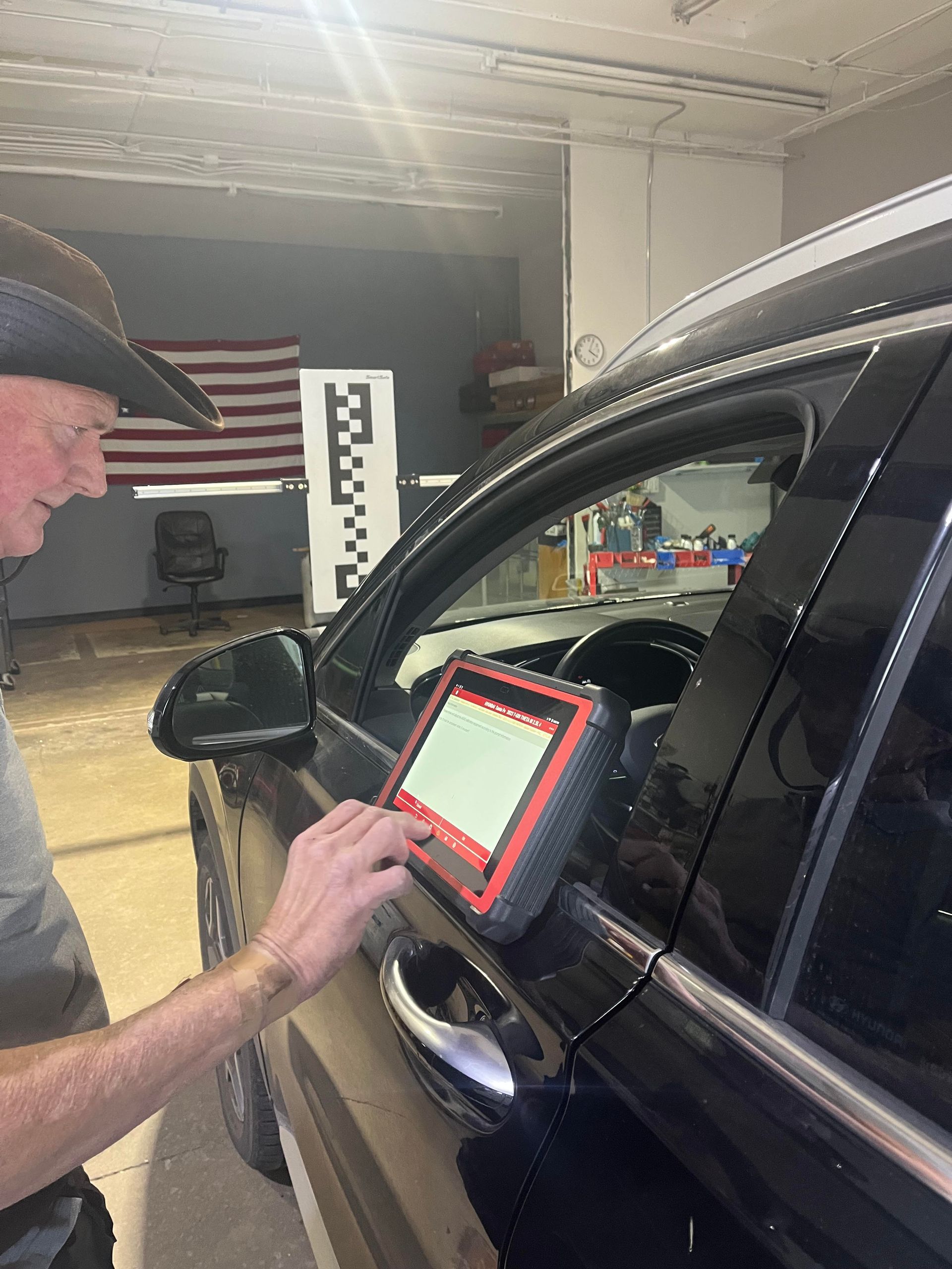 A man in a cowboy hat is working on a car in a garage.