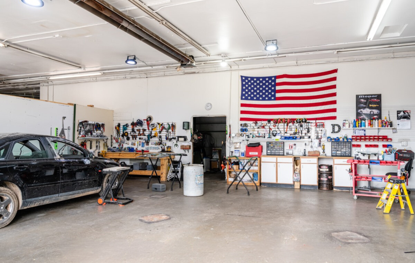 A car is parked in a garage with an american flag on the wall.