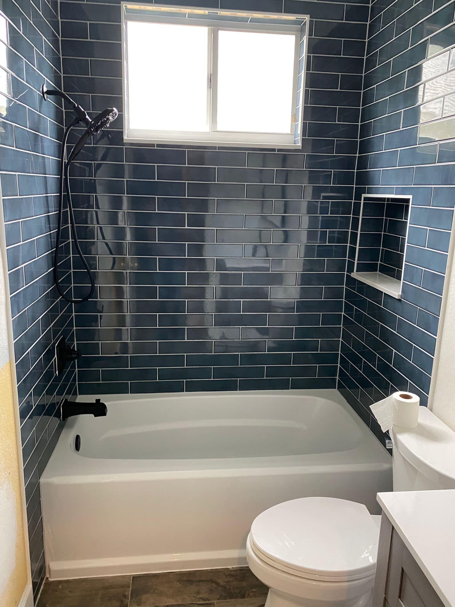 A bathroom with a tub , toilet , and window.