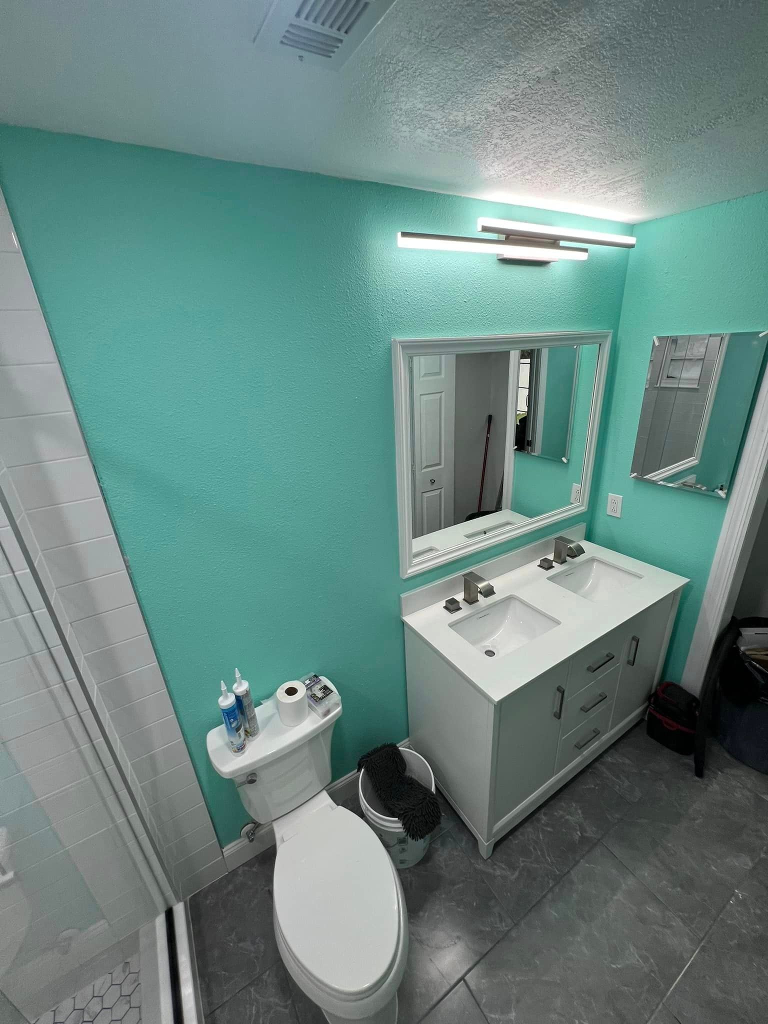 A bathroom with a toilet , sink and mirror.