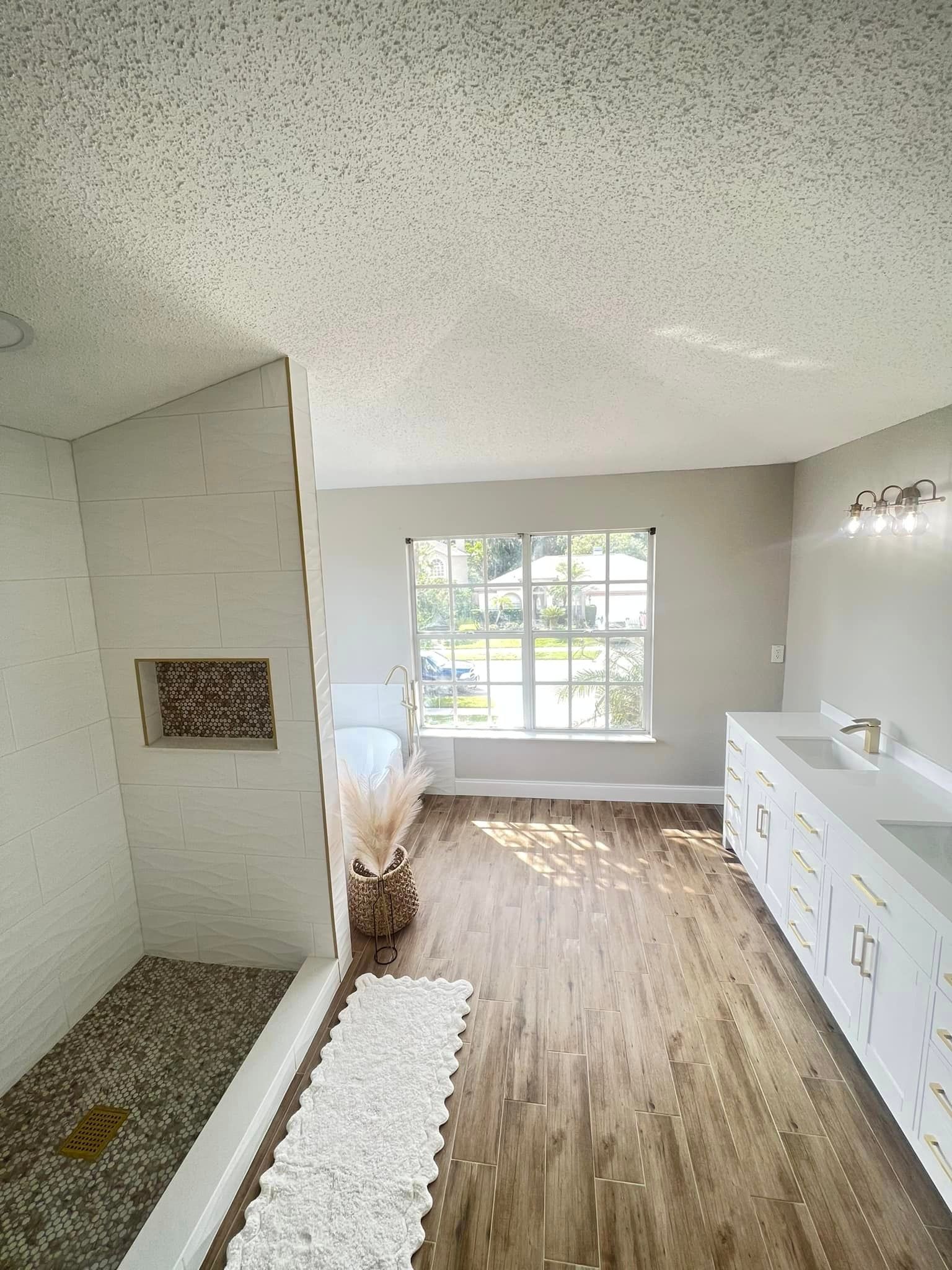 A bathroom with a walk in shower , sink , and window.
