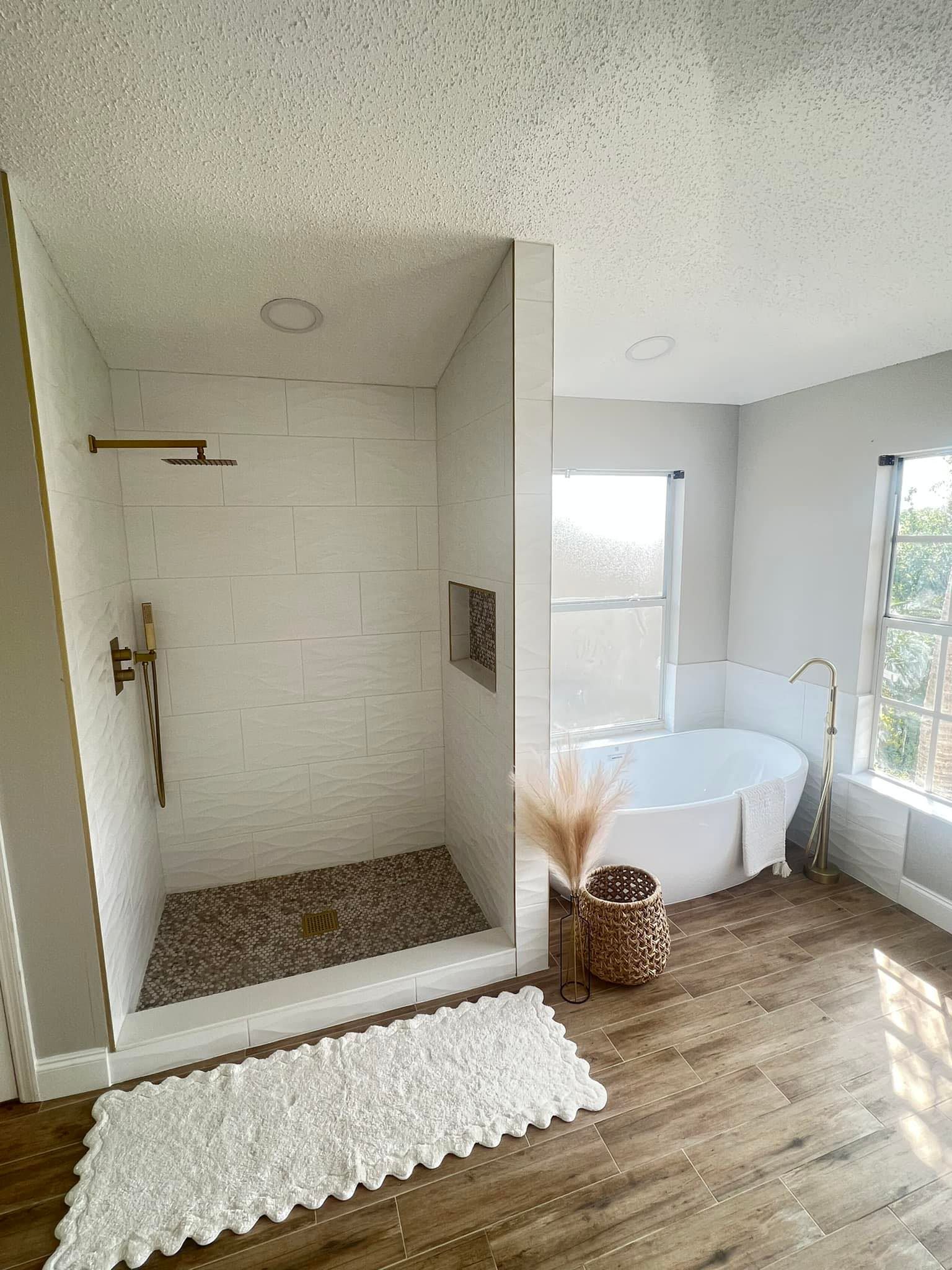 A bathroom with a tub , shower , and rug.