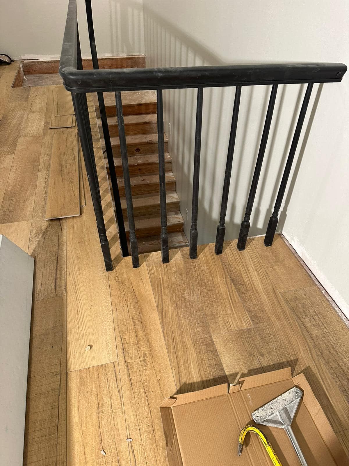 A wooden staircase with a metal railing is being installed in a house.