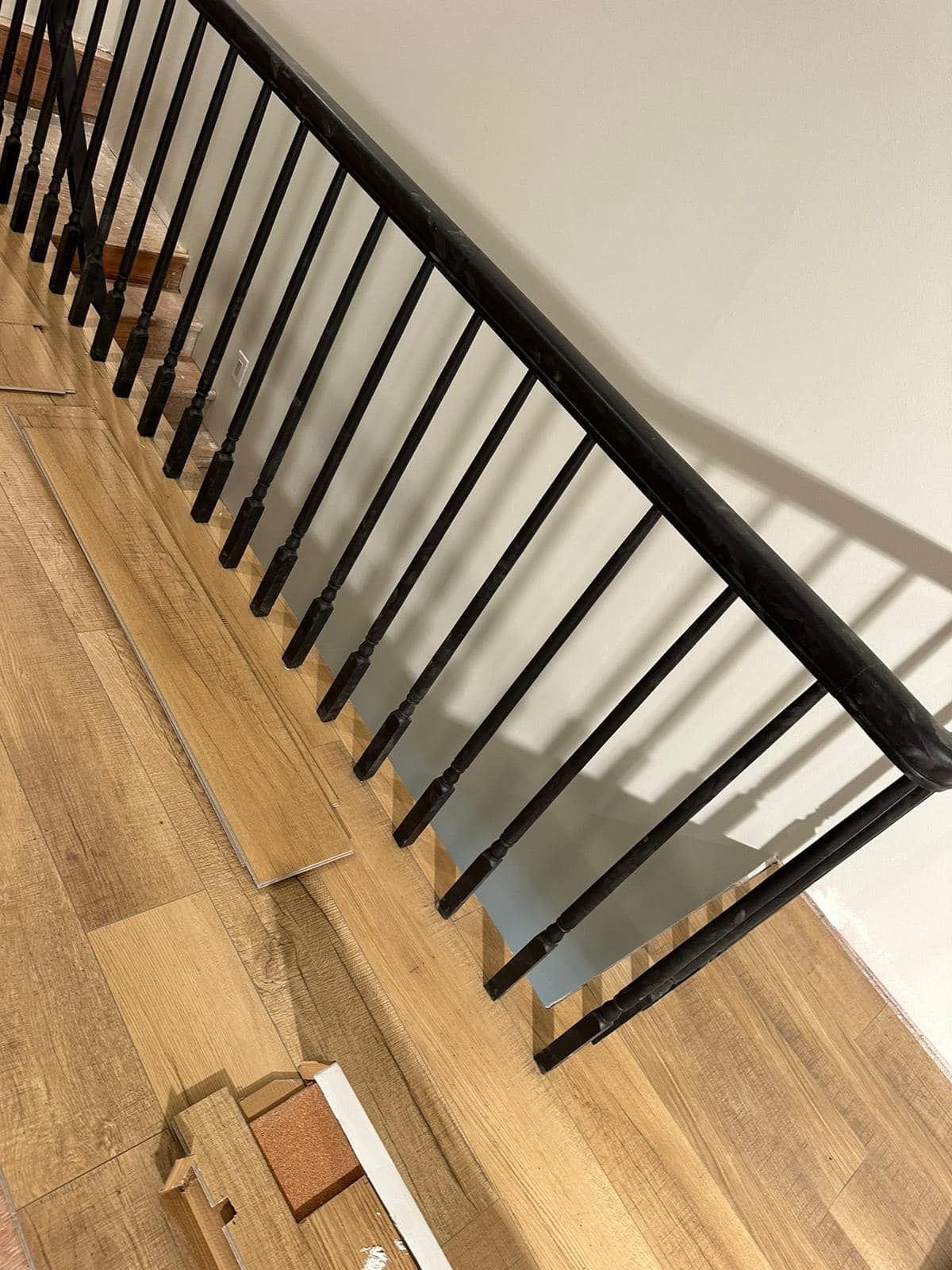 A close up of a wooden staircase with a black railing.