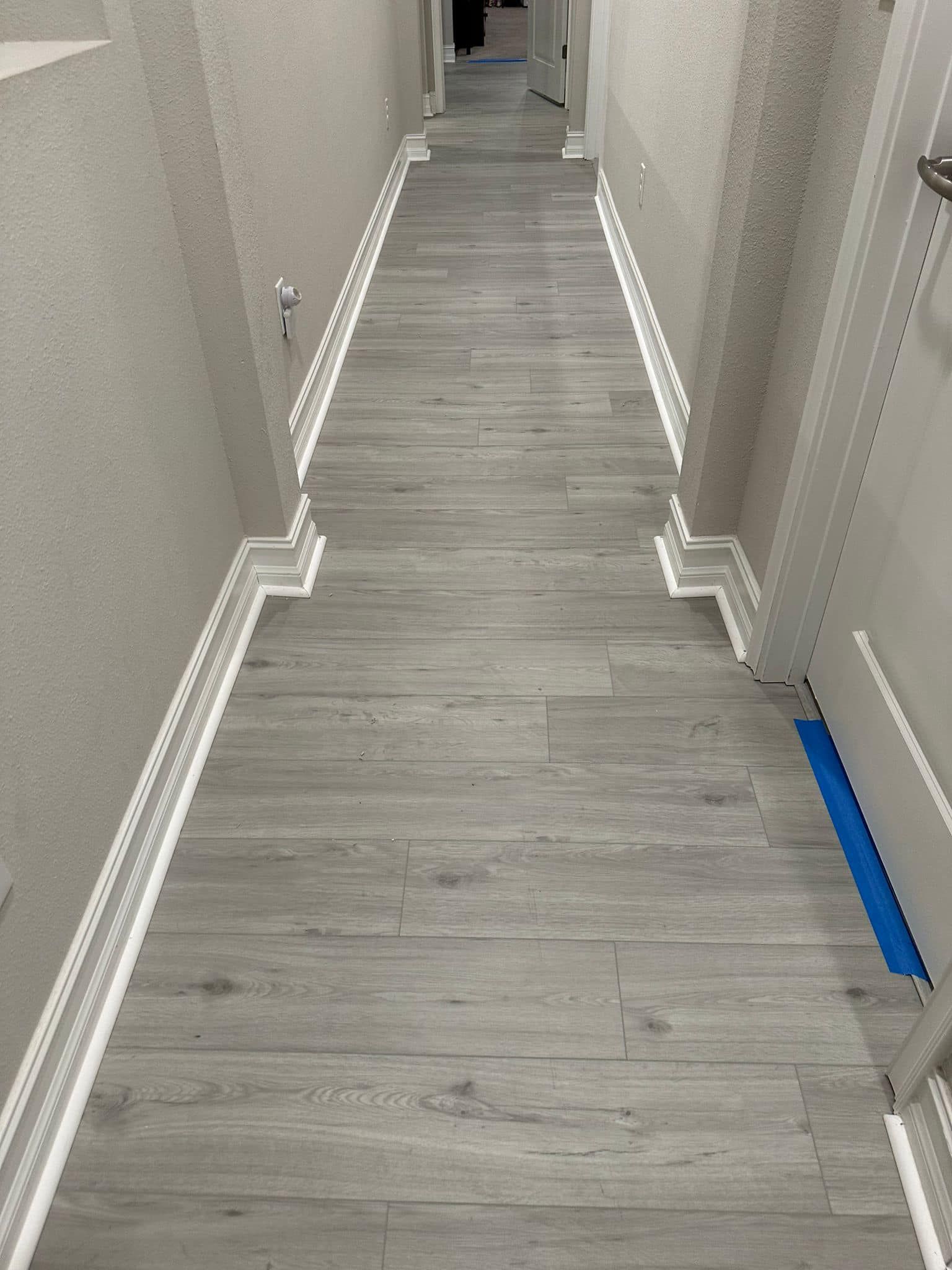 A long hallway with a wooden floor and white trim.