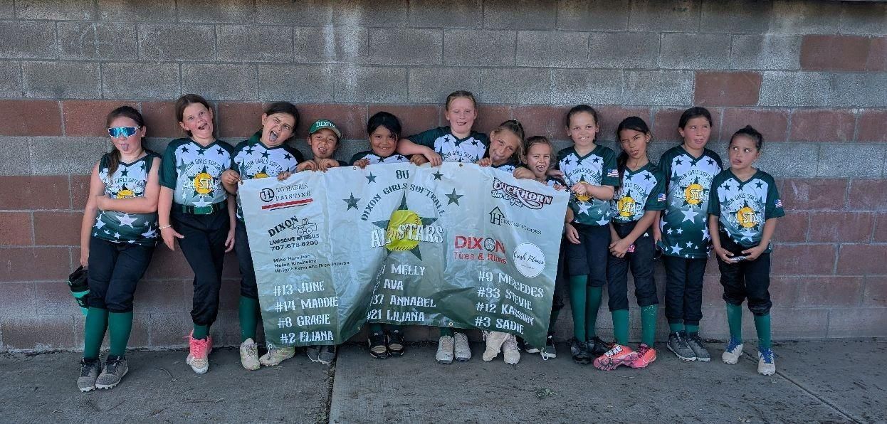 Baseball glove with ball on green grass, with blurred baseballs in the background.