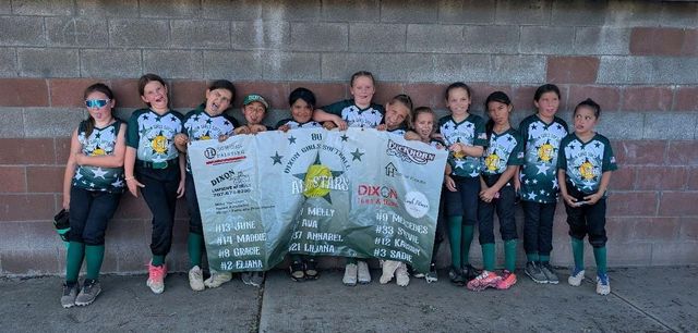 Baseball glove with ball on green grass, with blurred baseballs in the background.