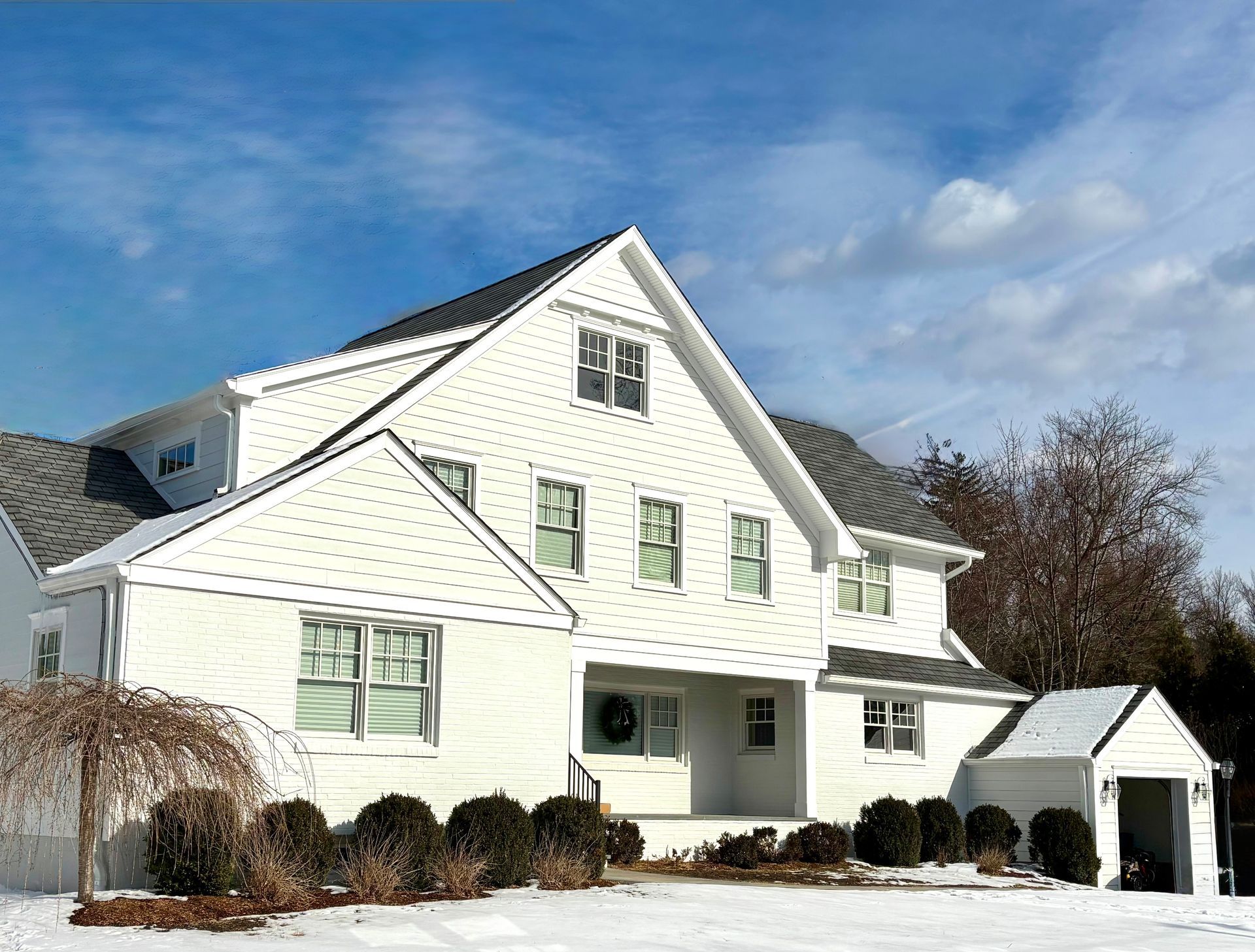 A large white house with snow on the ground in front of it