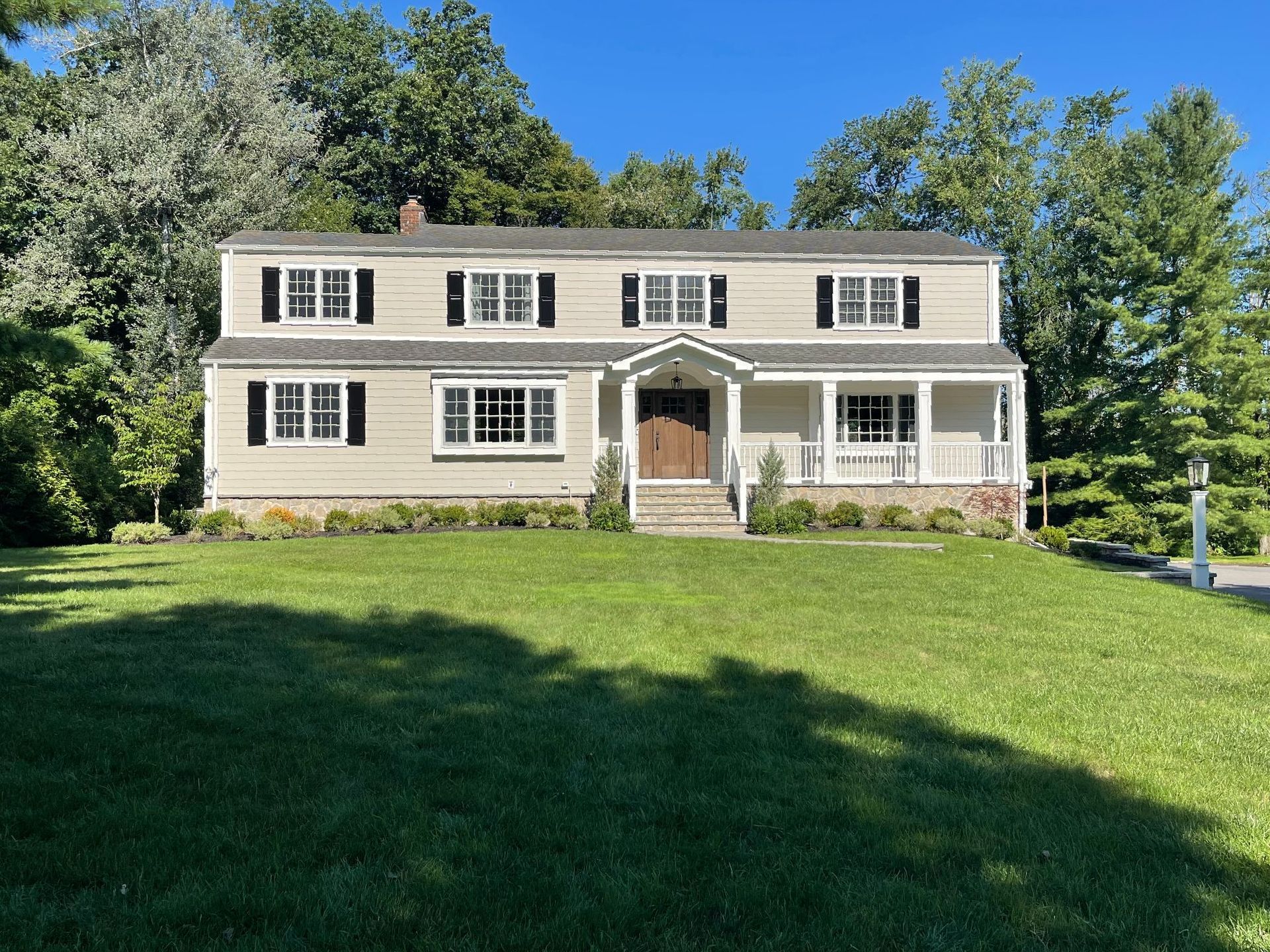A large house with a large lawn in front of it surrounded by trees.