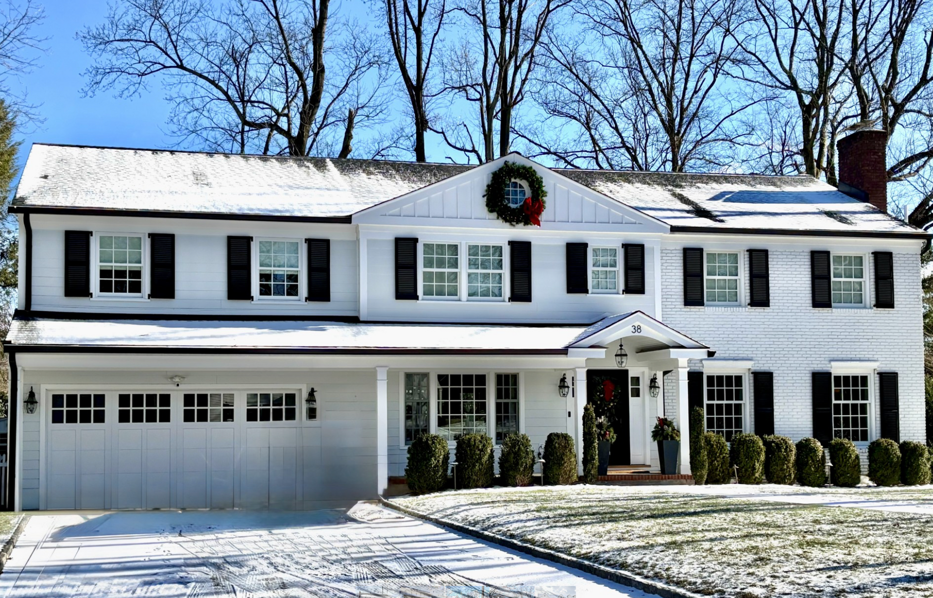 A large white house with black shutters and a wreath on top
