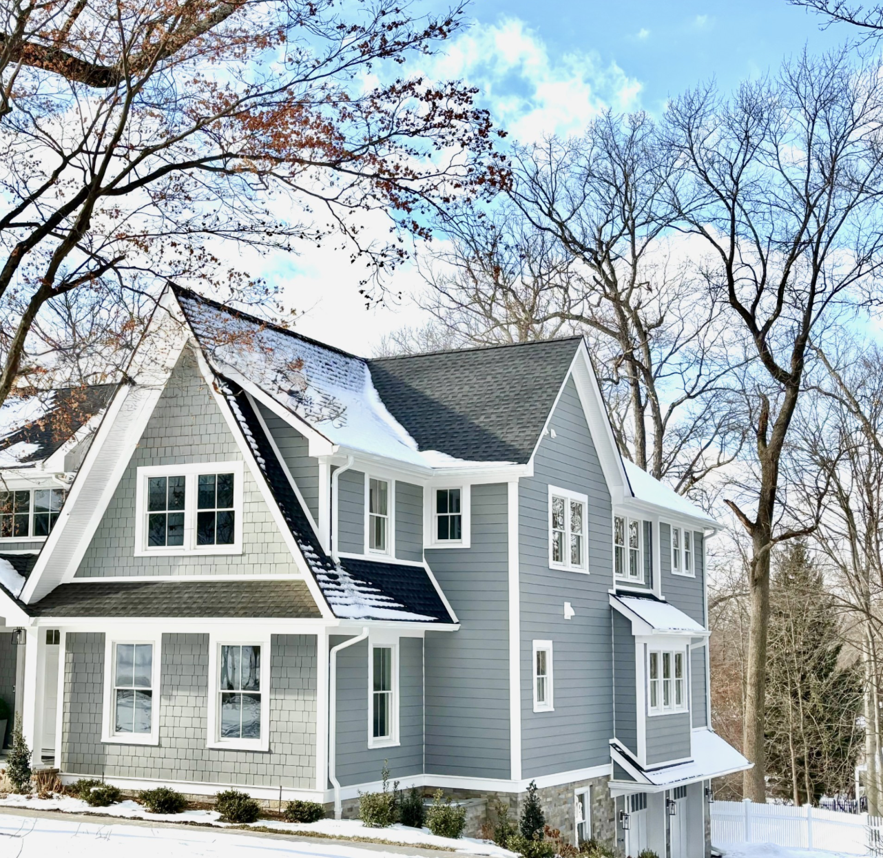 A large gray and white house with trees in the background
