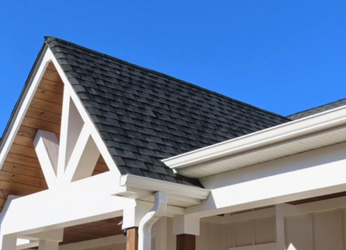 Dark gray shingled roof with white trim and wooden supports against a bright blue sky.