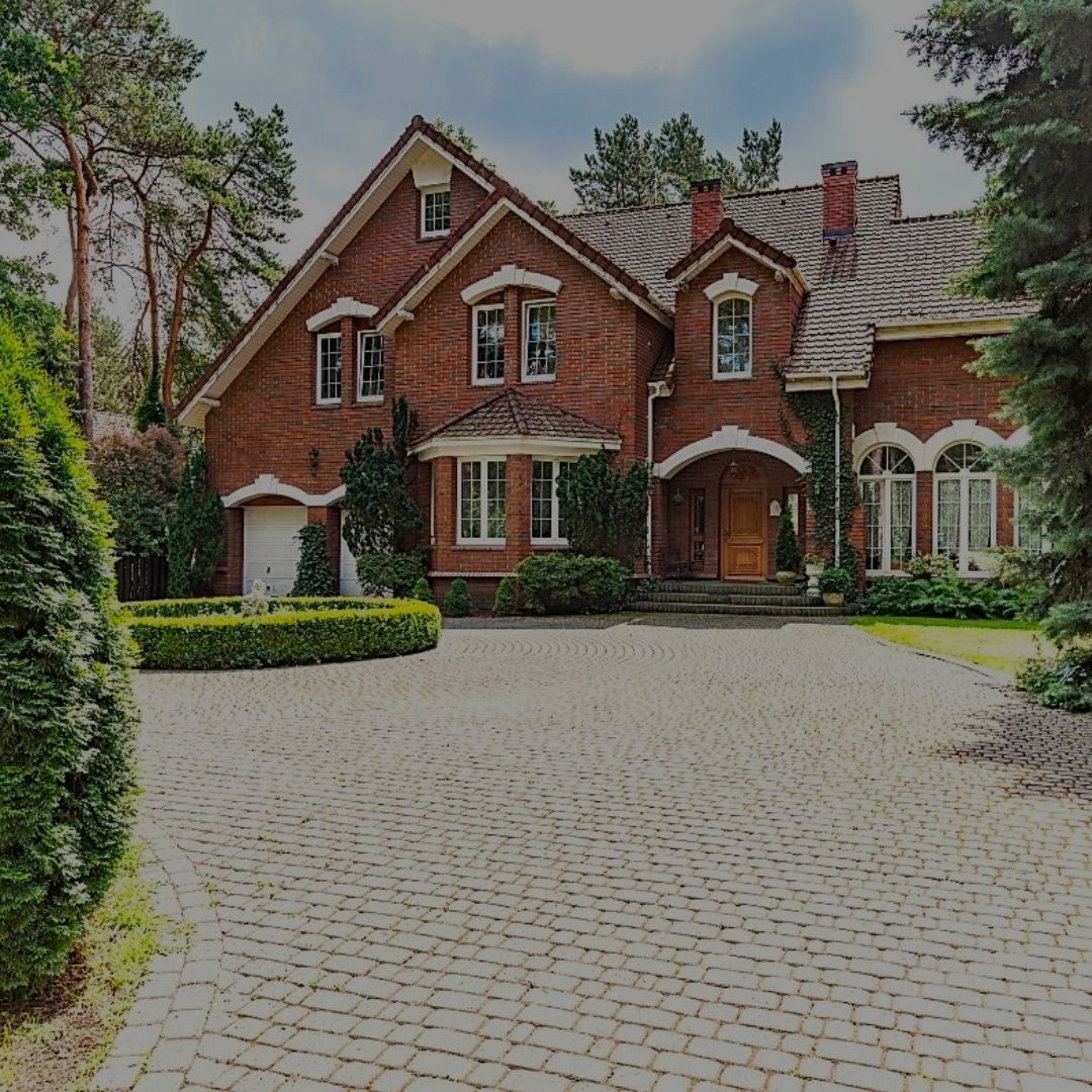A large brick house with a cobblestone driveway leading to it