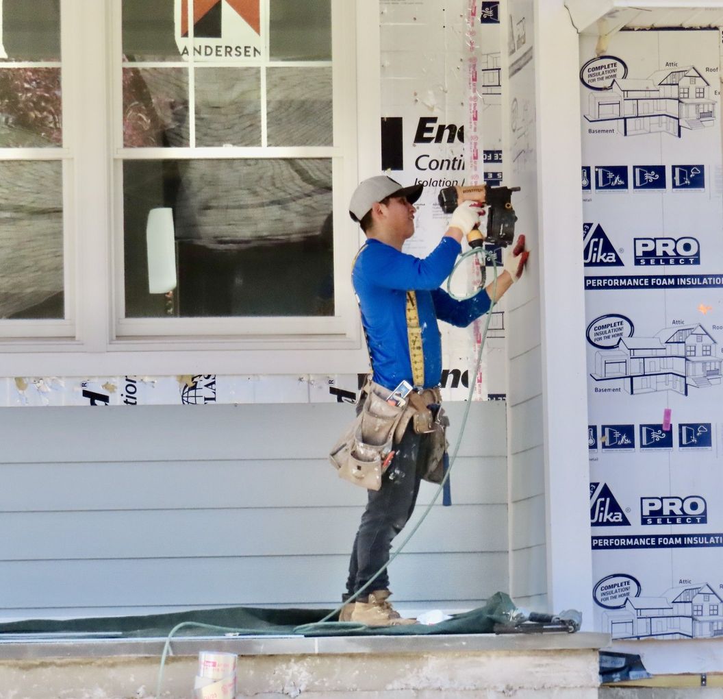 Construction worker using a nail gun on a building.
