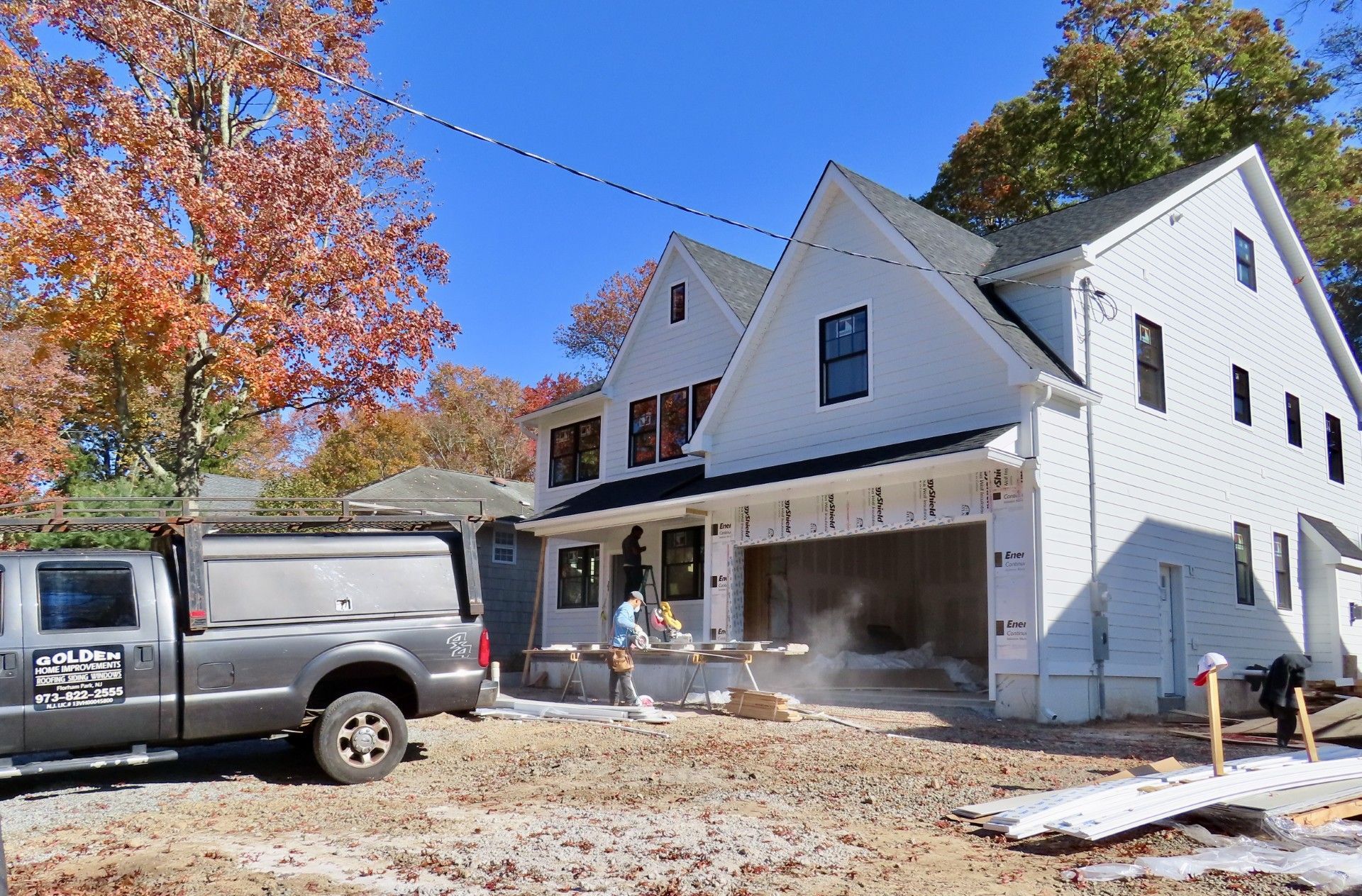 A white truck is parked in front of a house under construction