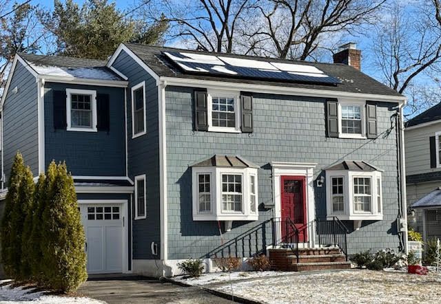 A blue house with a red door and solar panels on the roof.