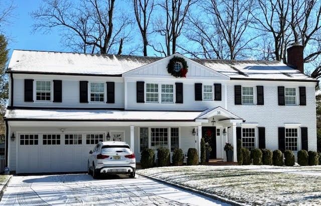 A white house with black shutters and a car parked in front of it.