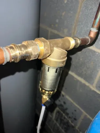 Brass water filter connected to copper pipes.