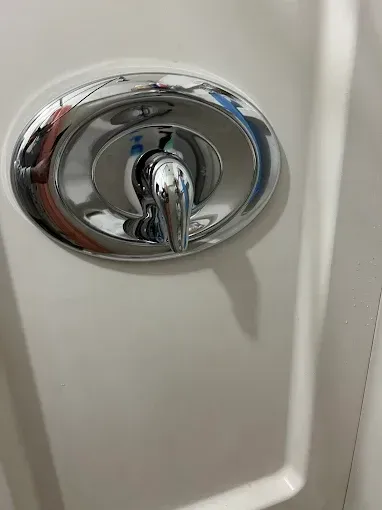 Chrome shower faucet on a white wall.