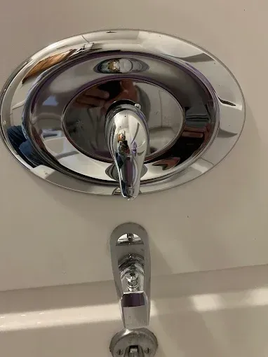 Chrome shower faucet with diverter on white tile.