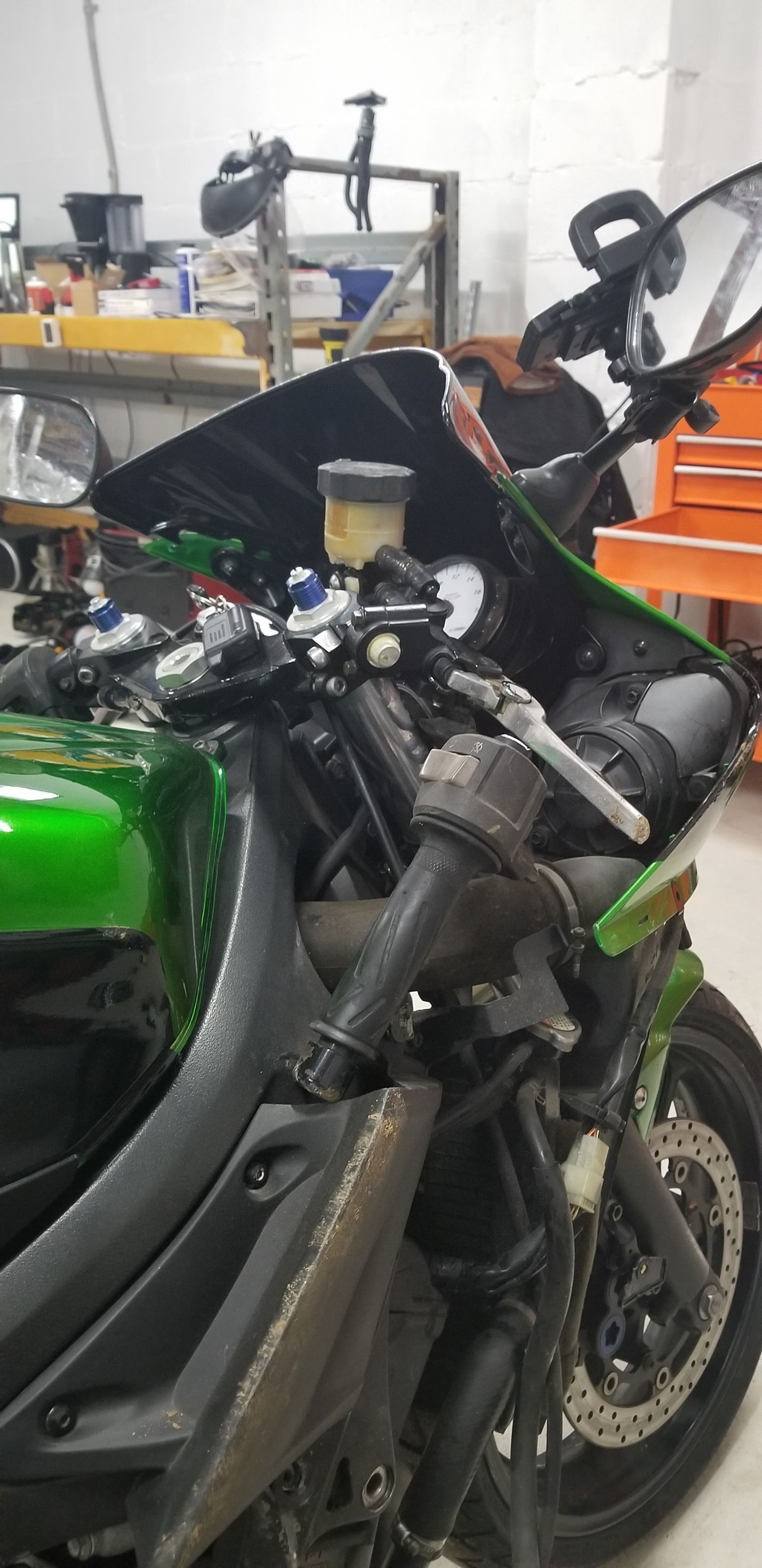 A green and black motorcycle is parked in a garage.