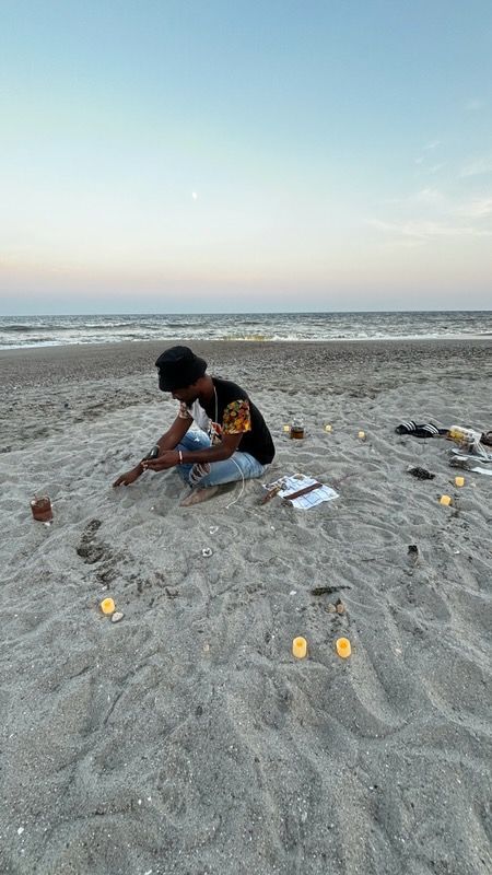 Person kneeling on beach, arranging sliced citrus; ocean in the background.