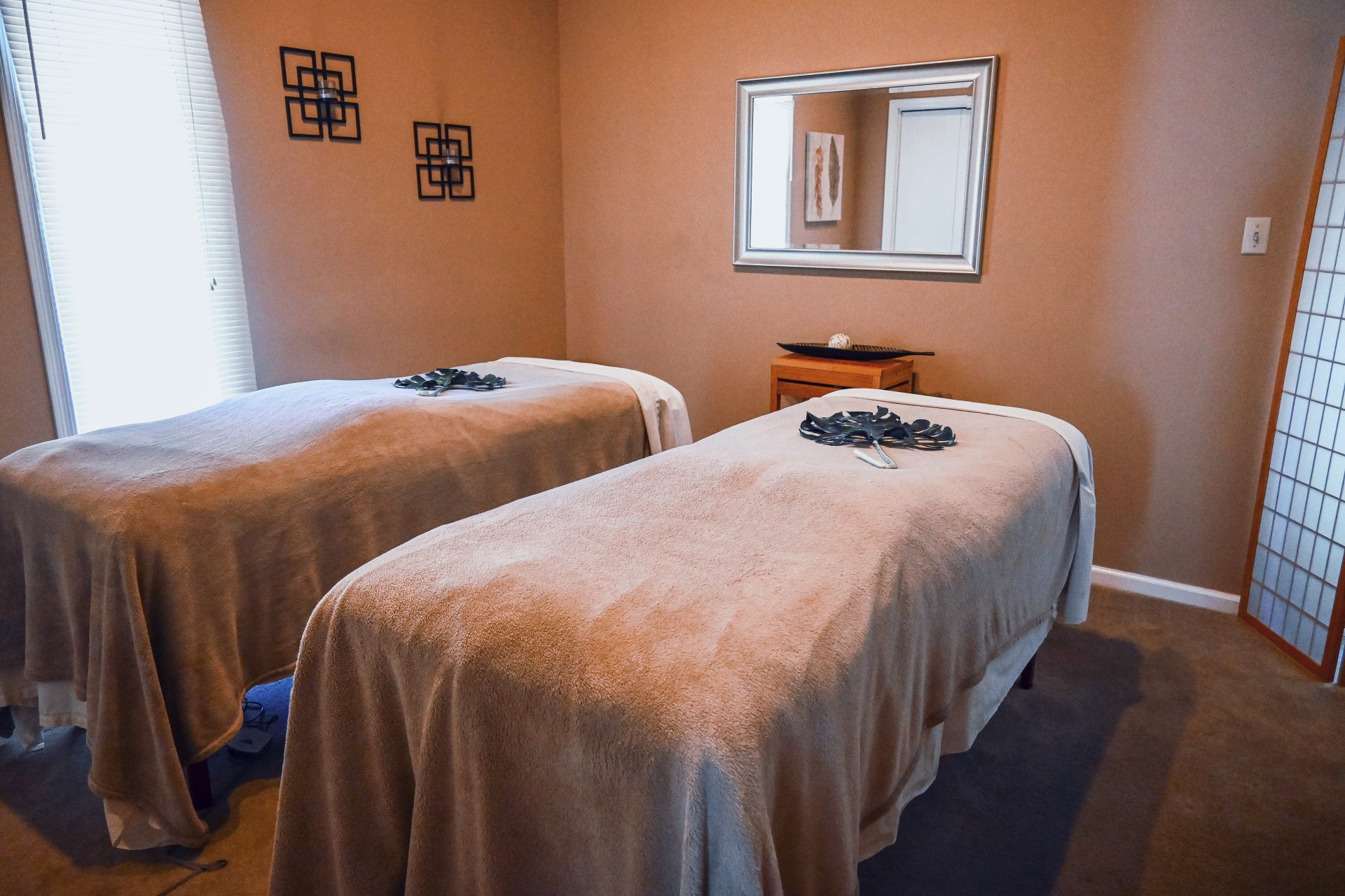 There are two massage beds in a room with a mirror.