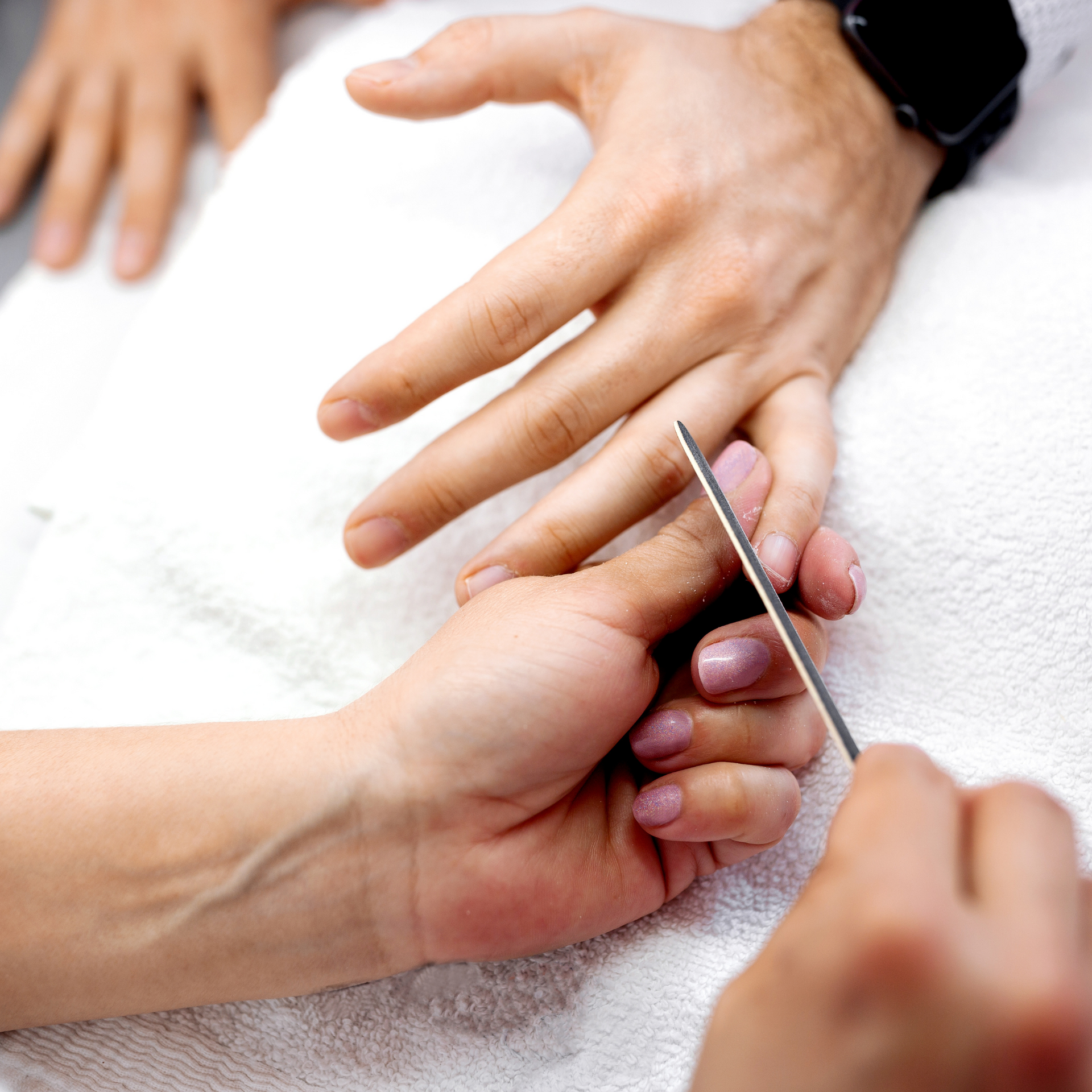 A man is filing a woman 's nails with a nail file