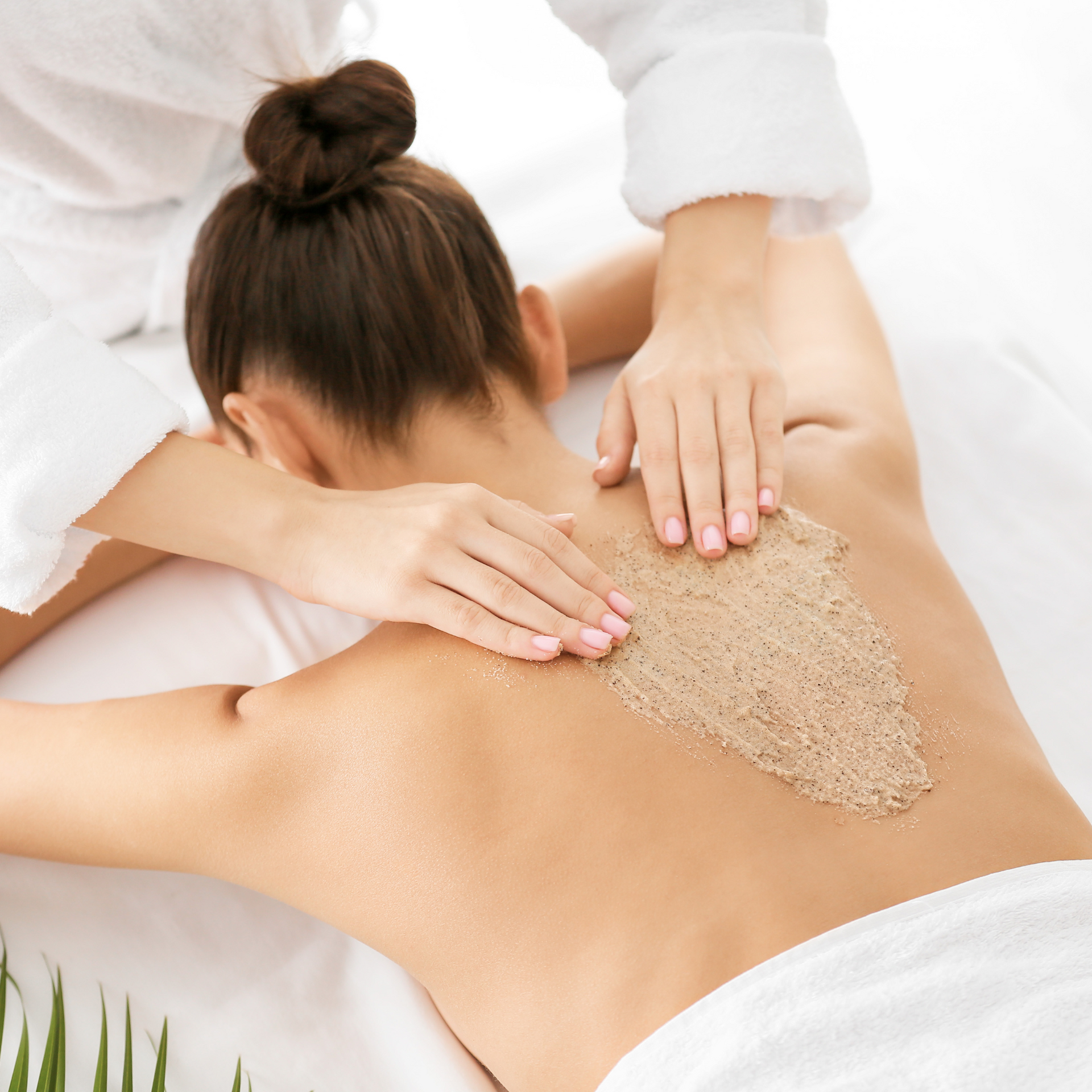 A woman is getting a massage with sand on her back