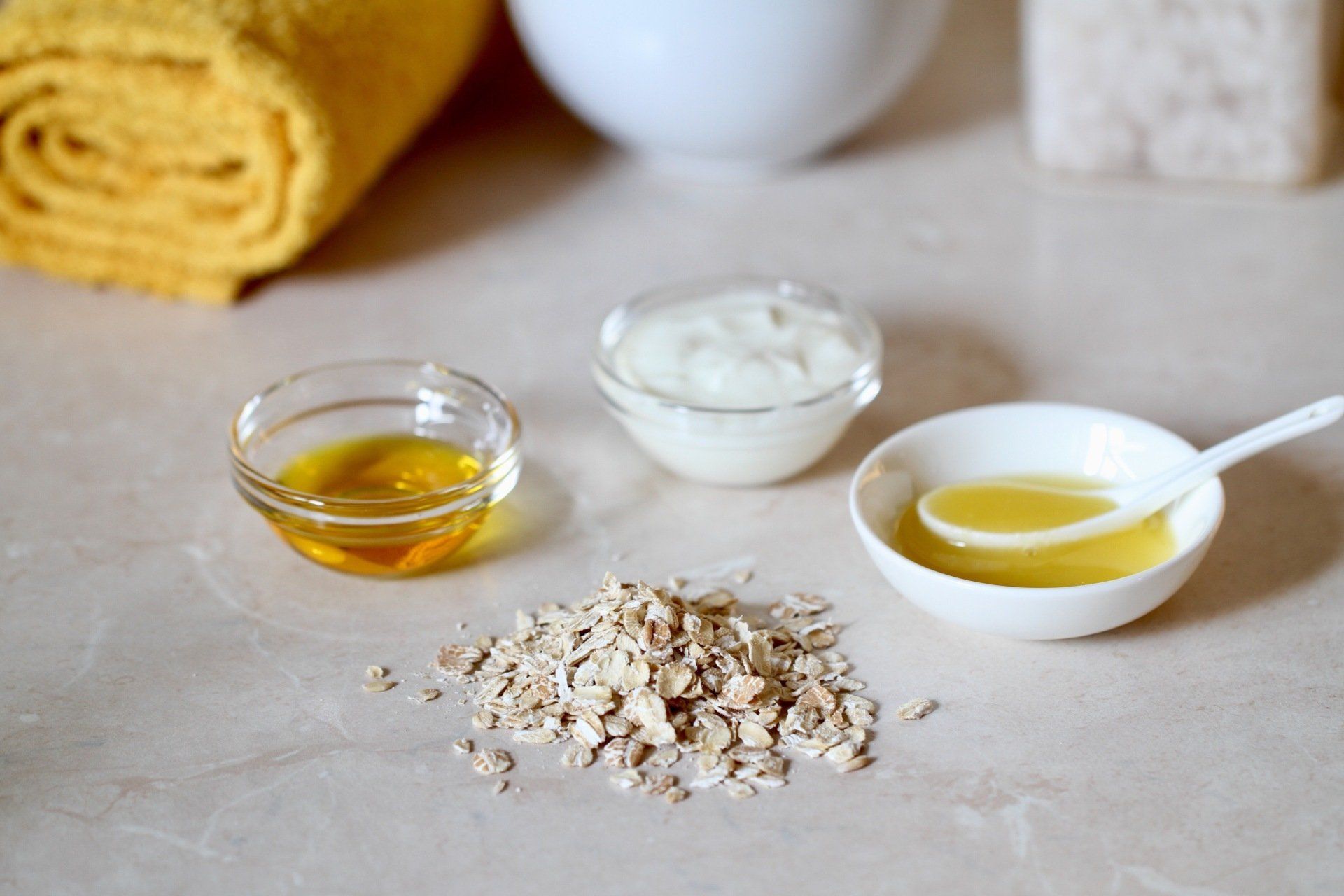 A table topped with bowls of oatmeal , honey , yogurt and oil.