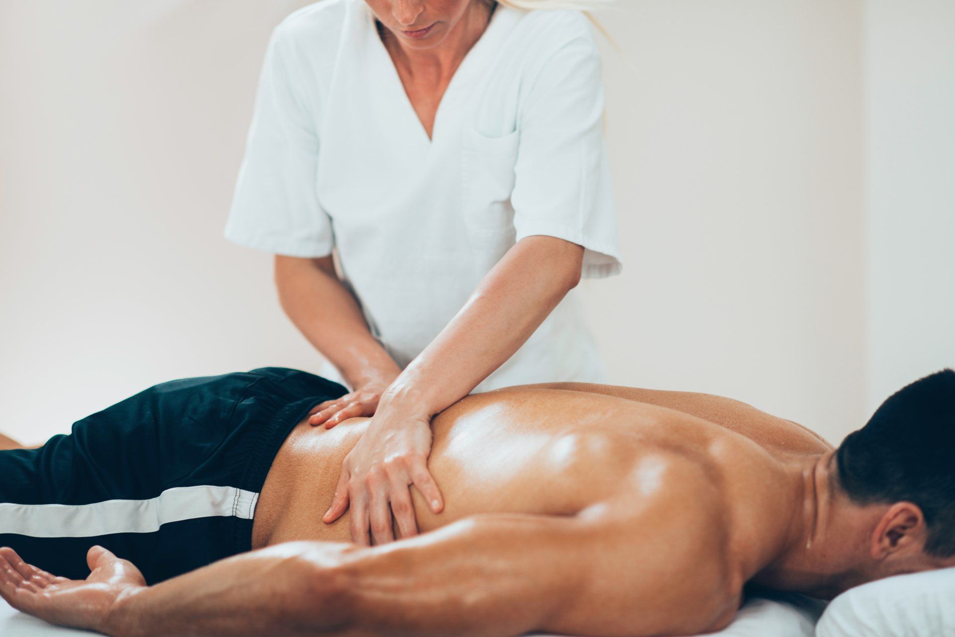 A man is laying on a bed getting a massage from a woman.