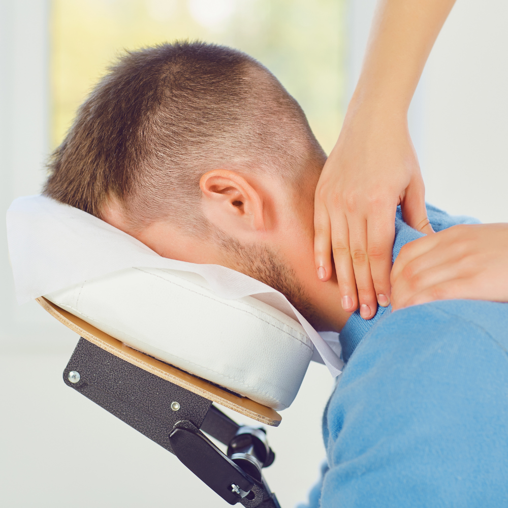A man is getting a massage from a woman in a chair
