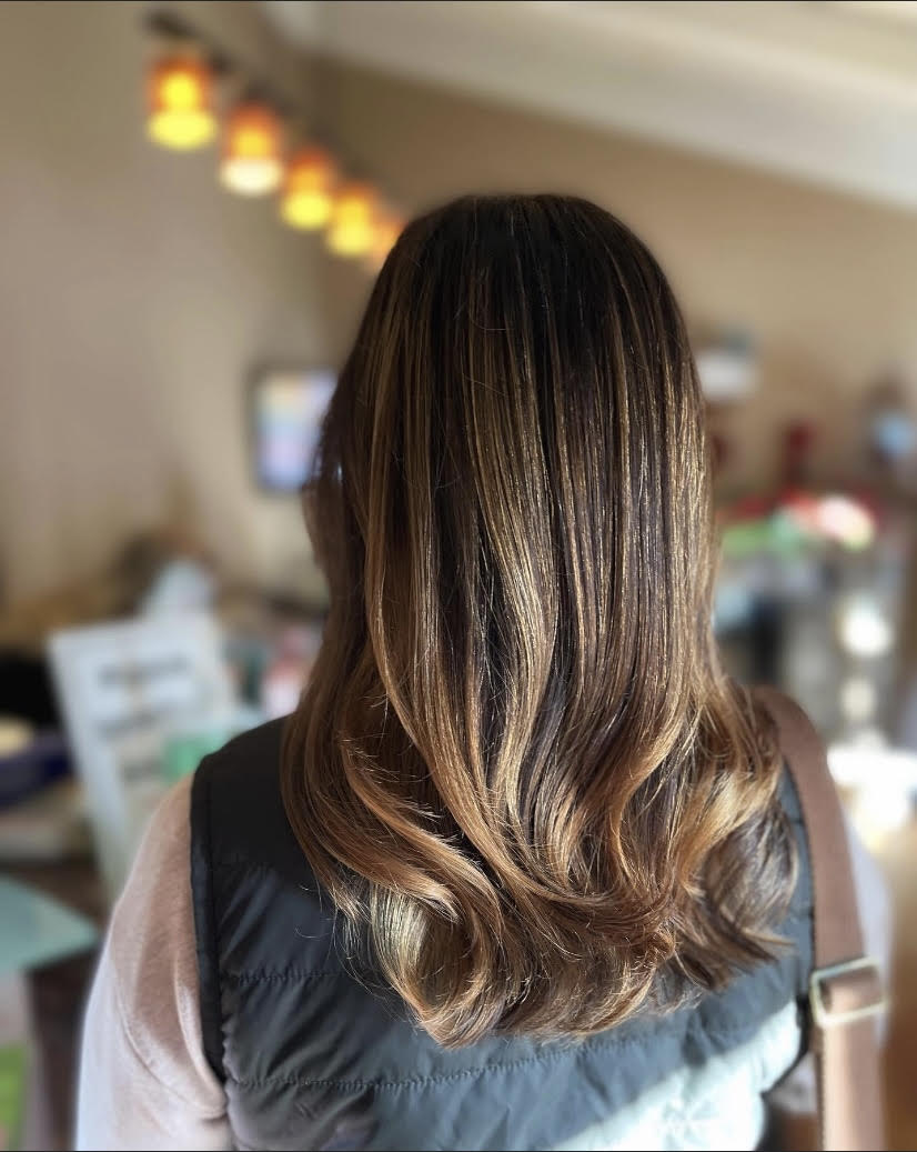 A woman with long brown hair is wearing a black vest.