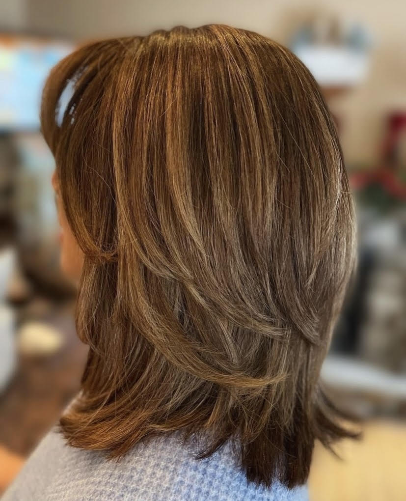 A woman with long brown hair is wearing a blue sweater.