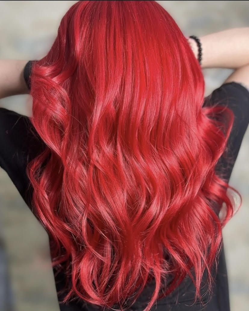 A woman with long red hair is wearing a black shirt.