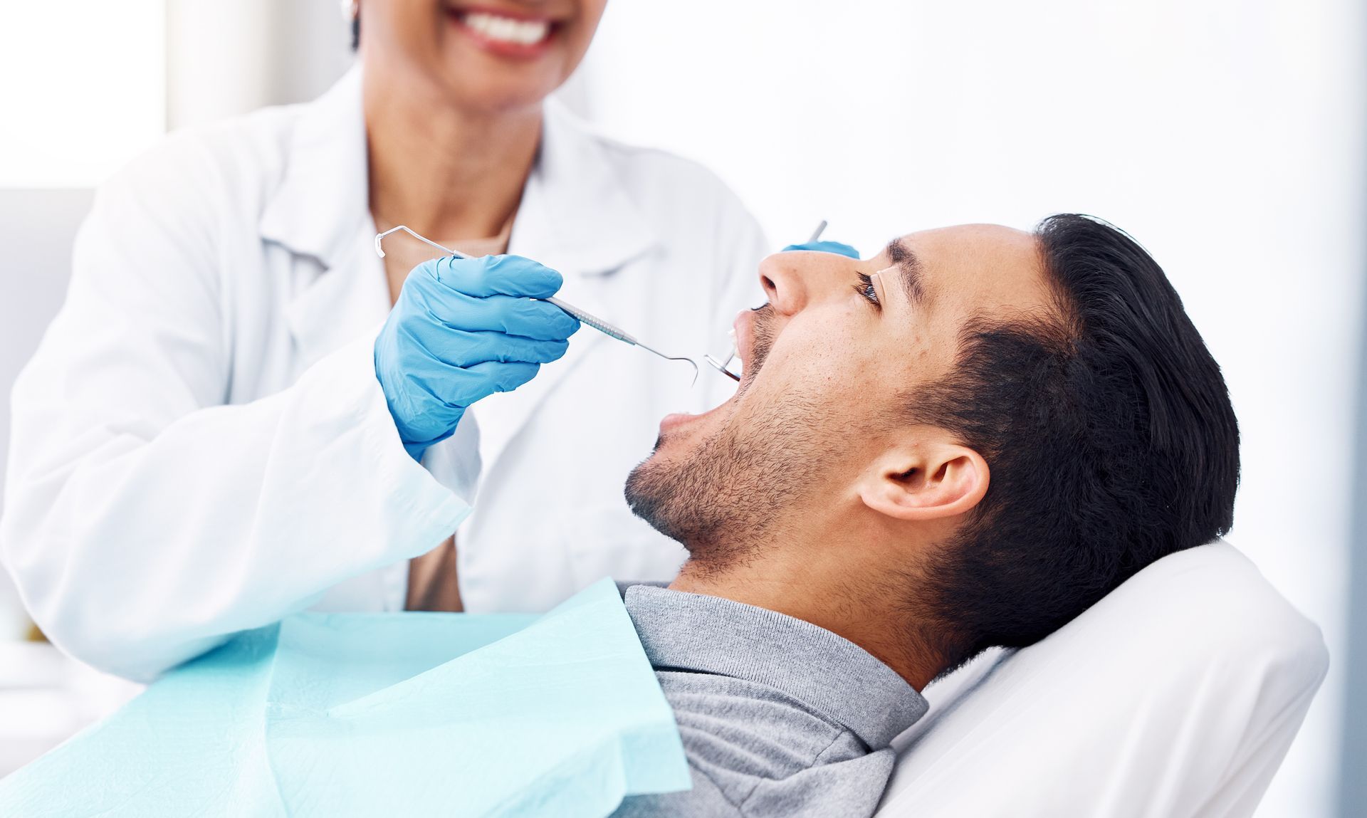 Dental professional examines a patient in the chair during an urgent dental appointment.
