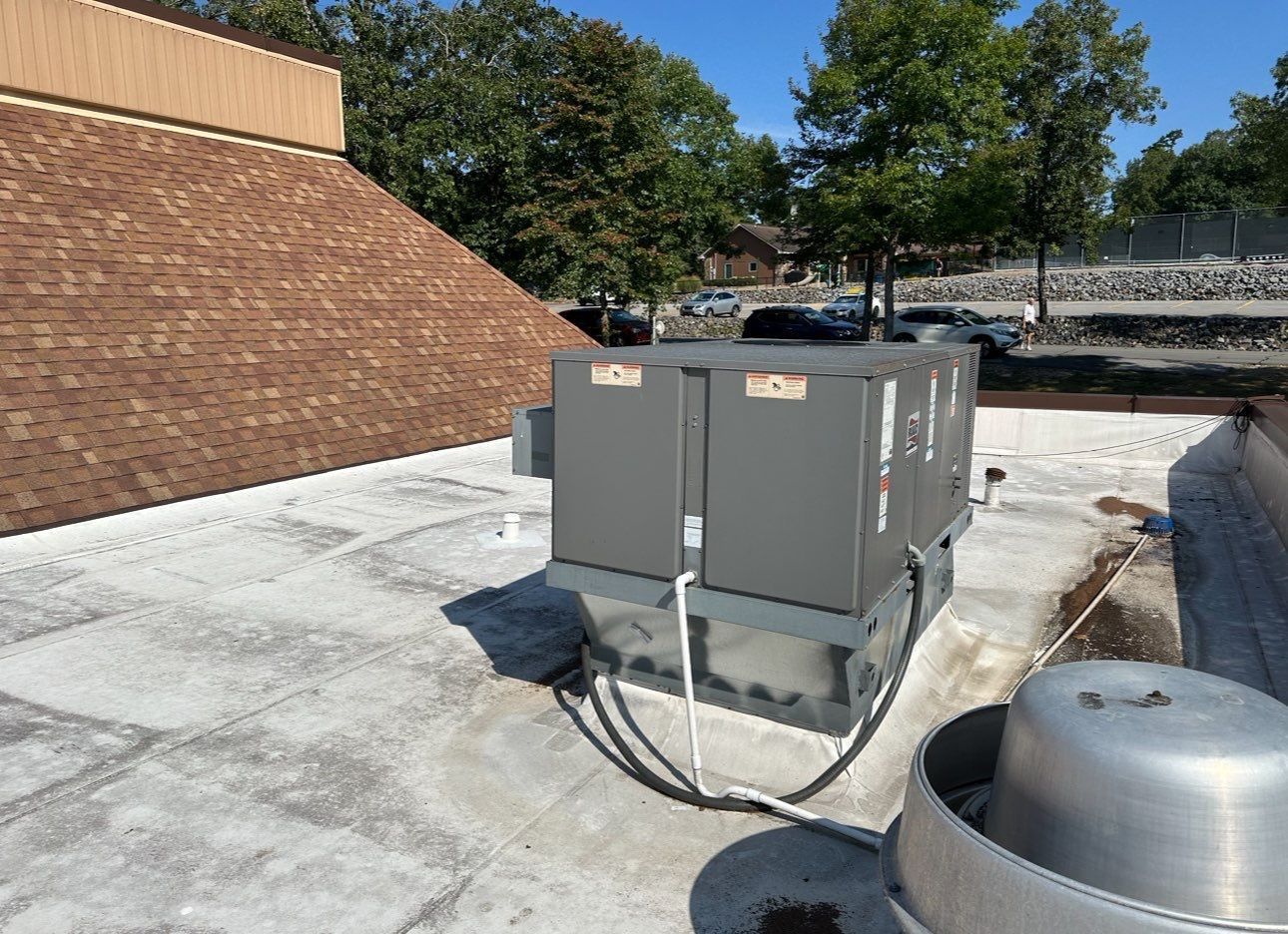 A rooftop air conditioner is sitting on top of a concrete roof.