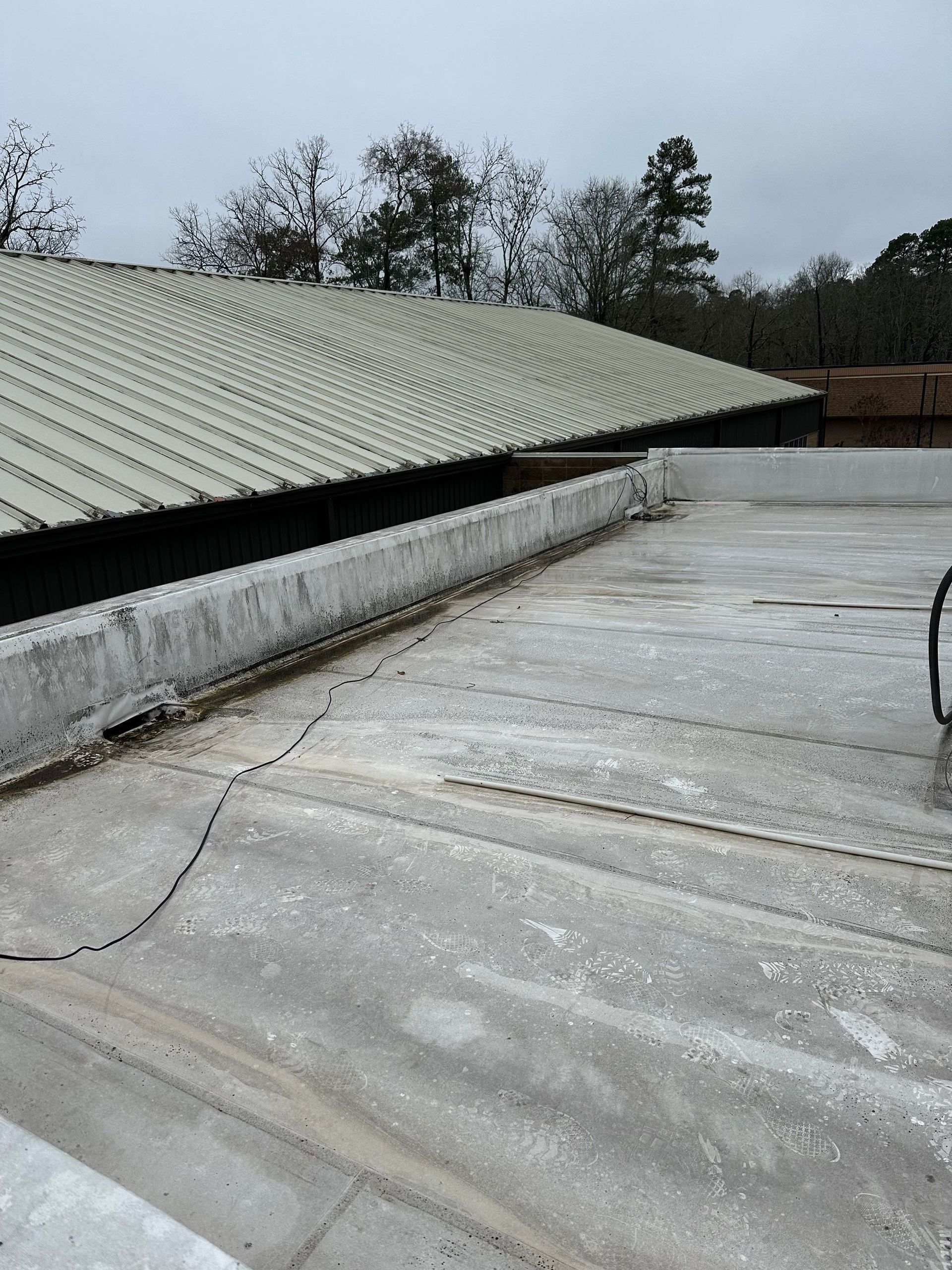 A roof with a vacuum cleaner on it and trees in the background.