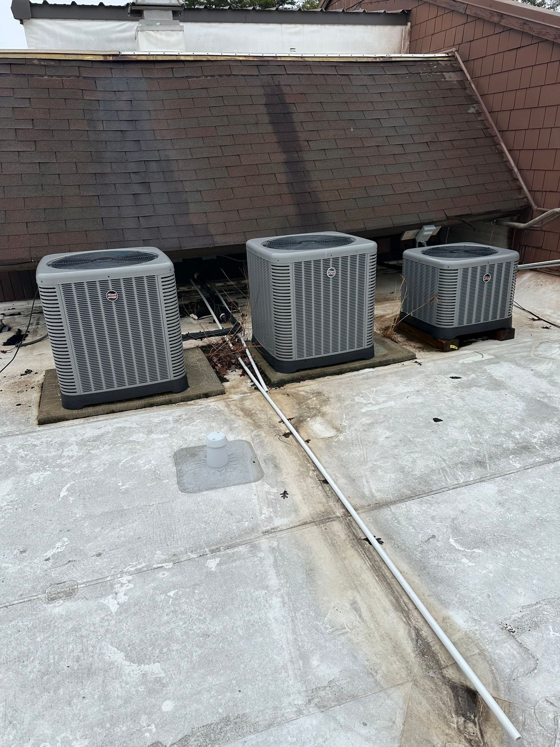 Three air conditioners are sitting on top of a roof.