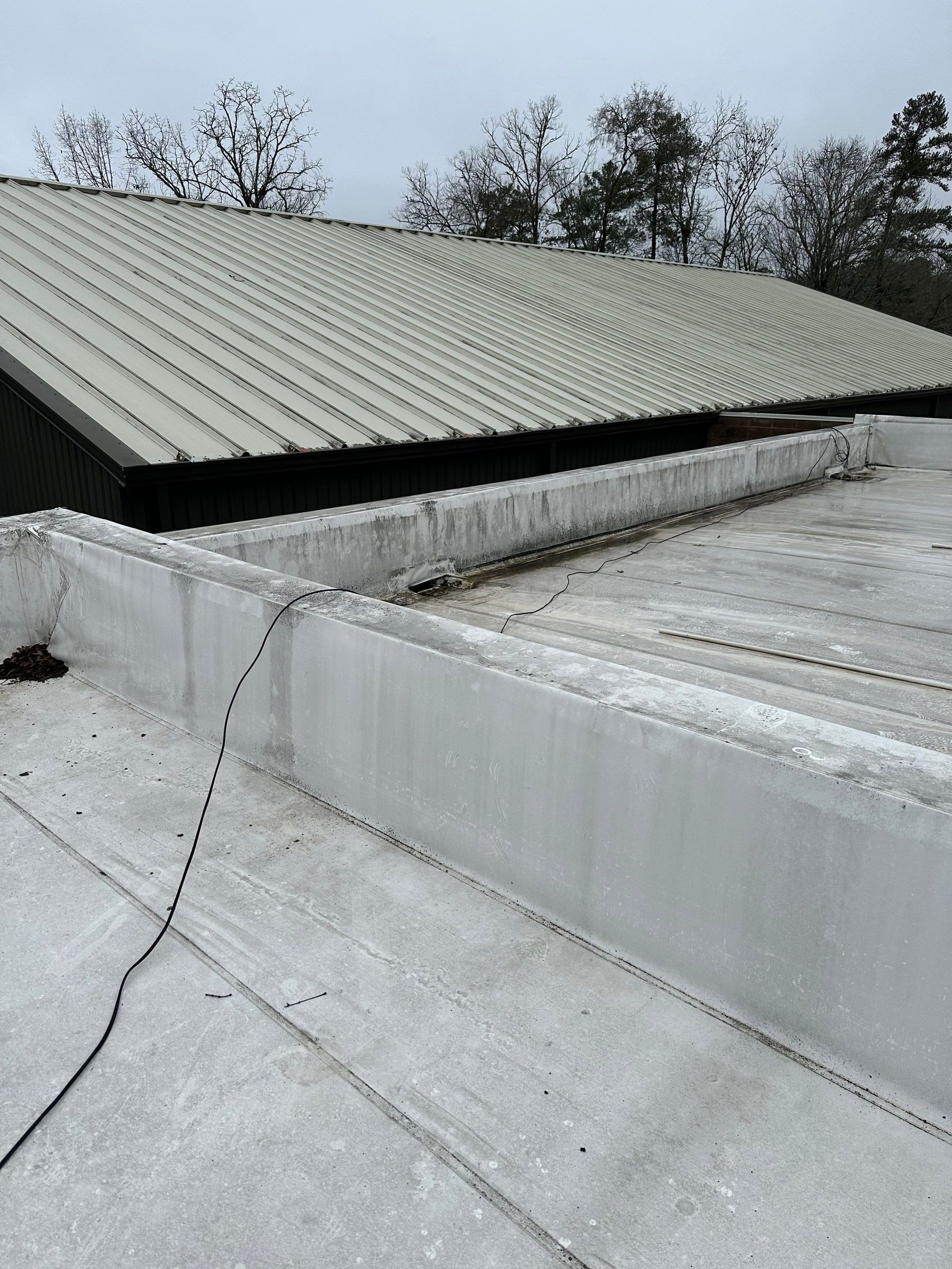 A white roof with a black roof and trees in the background.
