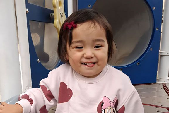 Happy toddler smiling on a playground slide during Montessori recess.