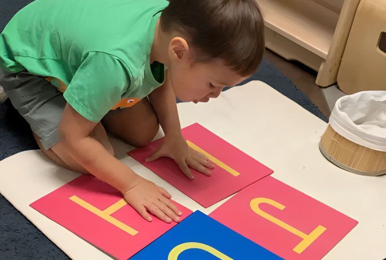 Montessori student working with large movable alphabet letter cards.