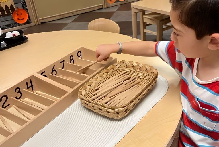 Montessori student working on the Spindle Boxes math material.